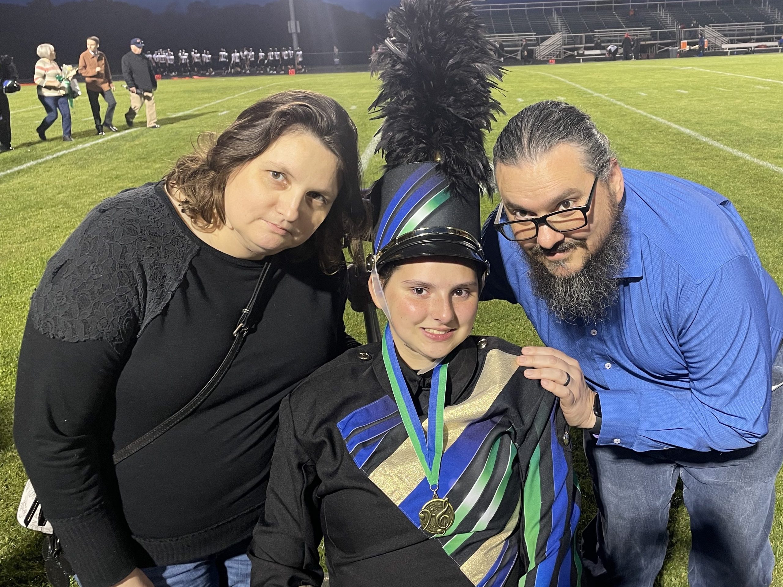 Senior night photo with my daughter in her band uniform in her wheelchair between my wife on the left and me on the right.